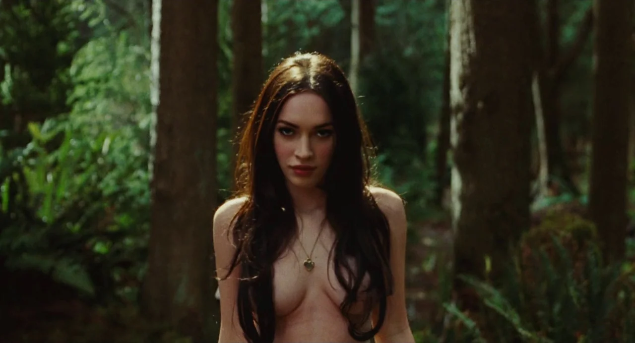 Jennifer’s Body (2009) movie still: medium — A dense green forest with tall trees and ferns surrounding the subject. The subject is positioned in…
