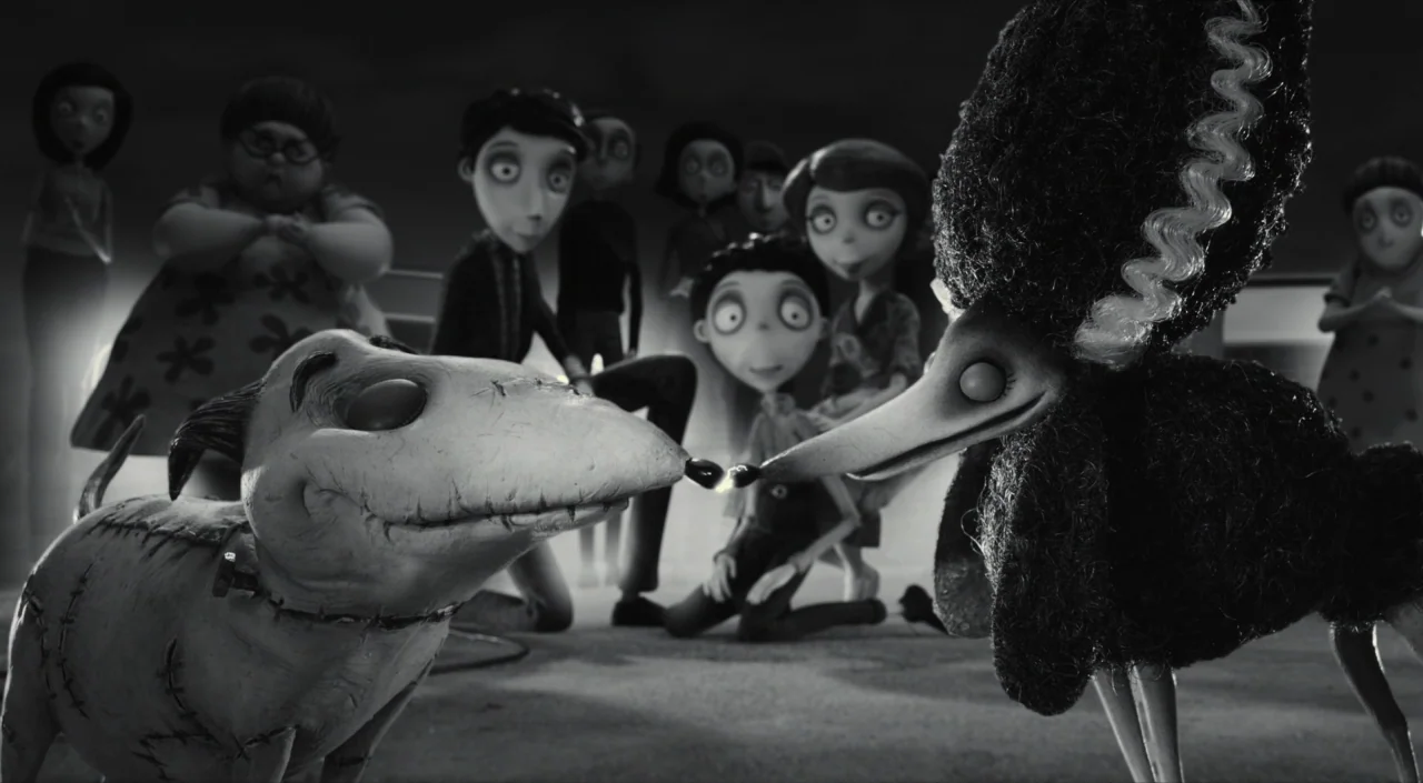 Frankenweenie (2012) movie still: medium — A group of stop-motion puppets stand inside a dimly lit space with dark backgrounds. Two canine puppets…