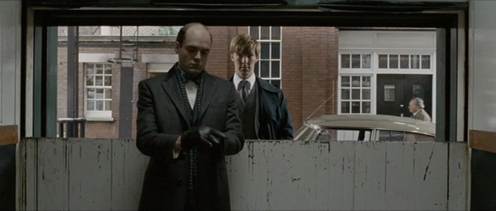 Tinker Tailor Soldier Spy (2011) movie still: medium — A industrial loading dock features a painted white wall with visible scratches and wear. Two…