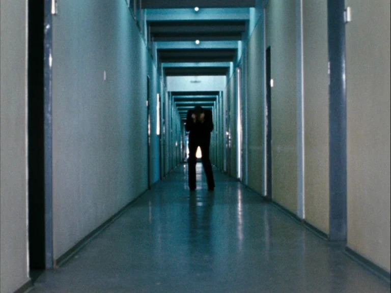 Making of: World On A Wire (1973) movie still: wide — A long, symmetrical hospital corridor features pale walls and repetitive doorway frames. A…