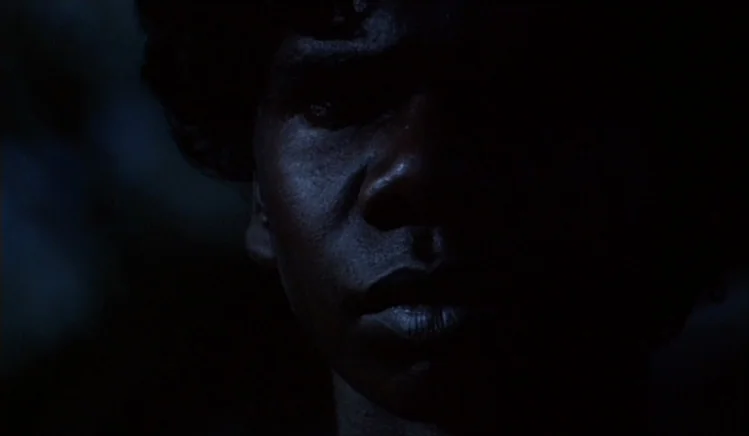 Walkabout (1971) movie still: closeup — A dark night setting with minimal light falling on a man's face. The subject turns his head slightly while…
