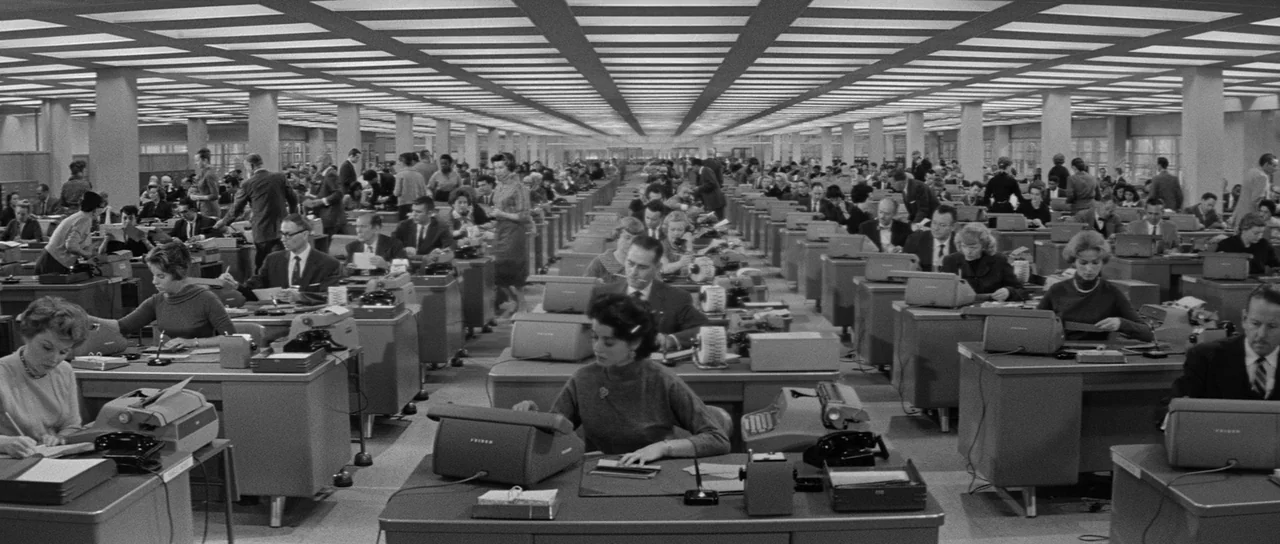 The Apartment (1960) movie still: wide — A vast, expansive open-plan corporate office filled with rows of identical metal desks. Numerous employees…