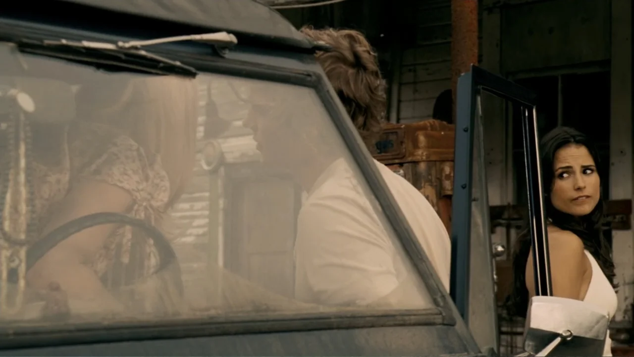 The Texas Chainsaw Massacre: The Beginning (2006) movie still: medium — An outdoor gas station setting with a parked vehicle and aged structural…