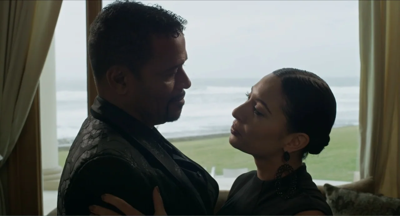 Instantes Capturados (2022) movie still: medium — An interior space with a large window looking out onto a grassy landscape. A man and a woman stand…
