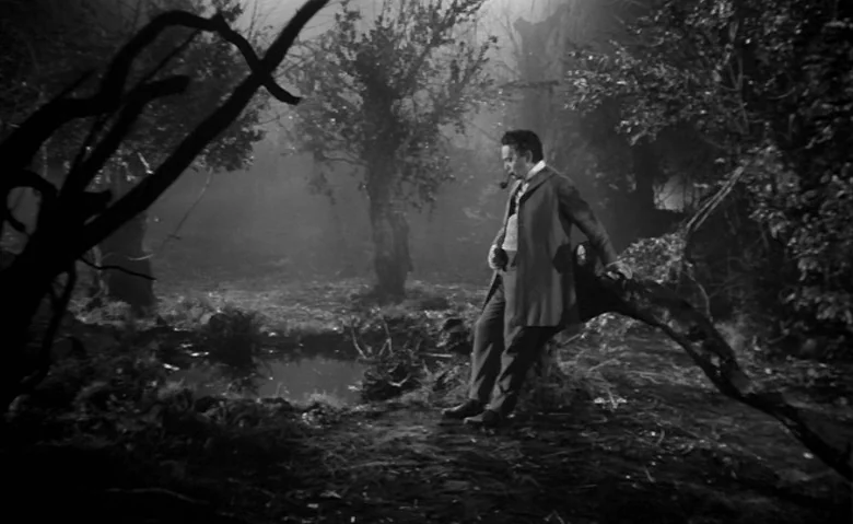 Black Sunday (1960) movie still: fullbody — A dense, foggy woodland area with a small pool of water in the foreground. A man stands alone in the…