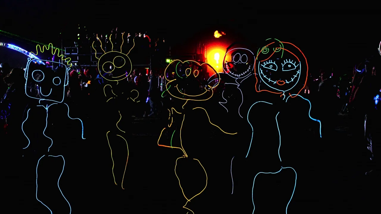 Awaken (2018) movie still: medium — An outdoor night venue features multiple people dressed in glowing electroluminescent wire suits. The figures…