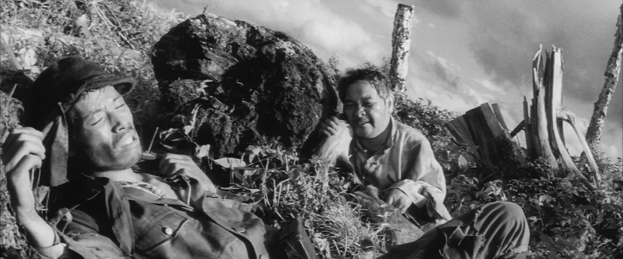 The Human Condition III: A Soldier’s Prayer (1961) movie still: medium — A rugged outdoor terrain features cut tree stumps and wild overgrown…