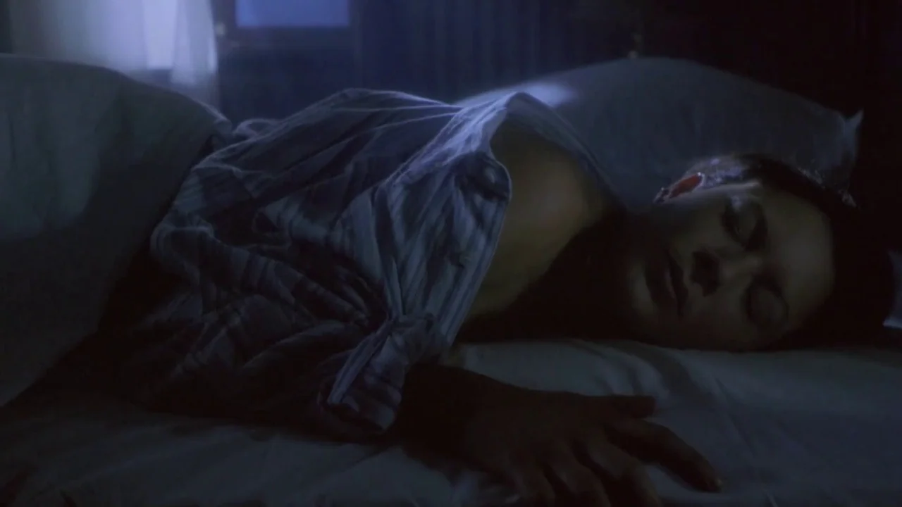 Hellraiser: Deader (2005) movie still: medium — A dimly lit room at night with a person sleeping in a bed. The subject lies under white covers…