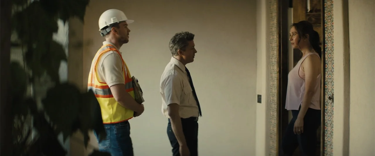 Those Who Wish Me Dead (2021) movie still: medium — A residential hallway features plain off-white walls and a doorway with decorative trim. Two men…