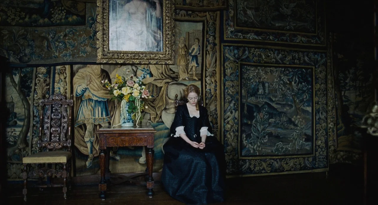 The Favourite (2018) movie still: wide — A dark, wood-paneled room is heavily decorated with large, ornate 18th-century woven wall tapestries. A…