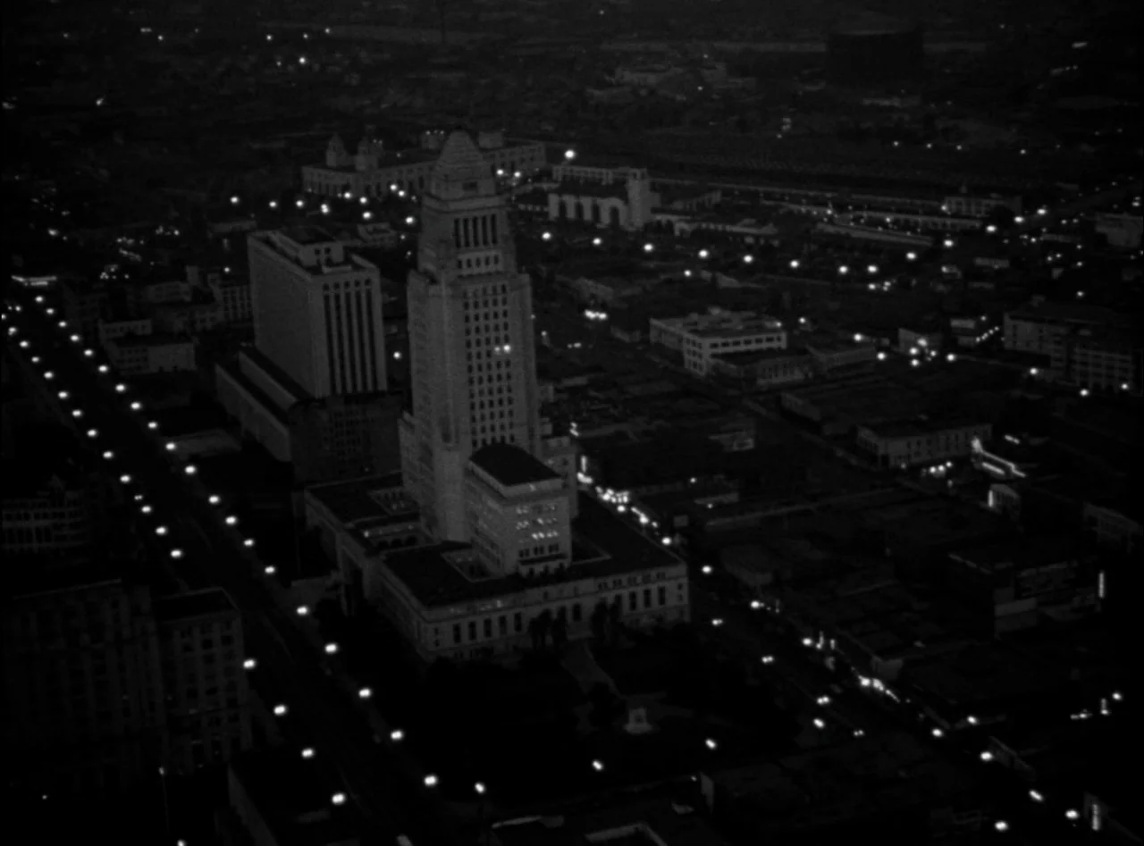Criss Cross (1949) movie still: establishing — An aerial view of a metropolitan city center at night with grid streets. The prominent central…
