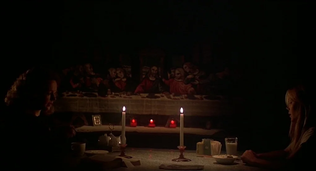 Carrie (1976) movie still: wide — A dark dining room features a large painting of The Last Supper on the wall. Two women sit across from one another…