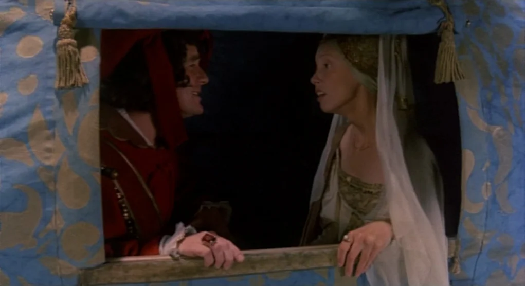 Time Bandits (1981) movie still: medium — Two individuals occupy a horse-drawn carriage adorned with blue and gold floral patterns. A man in a red…