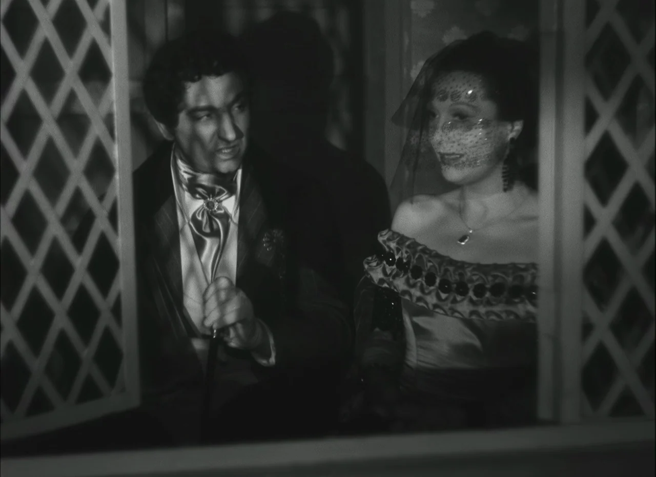 Les Enfants Du Paradis (1945) movie still: medium — A dark carriage interior with wooden lattice framework visible in the foreground. A man and a…