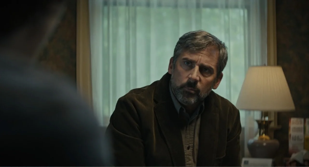 Beautiful Boy (2011) movie still: medium — A dimly lit office features a window with white curtains and a table lamp. A man sits at a desk during…