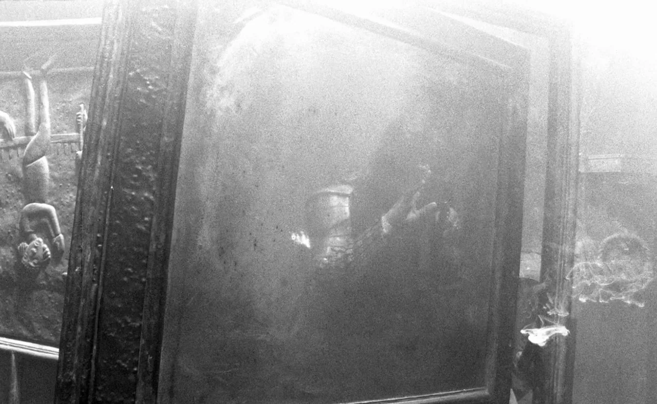 Hard To Be A God (2013) movie still: medium — A dark gallery space contains a large framed artwork under heavy atmospheric haze. The artwork…