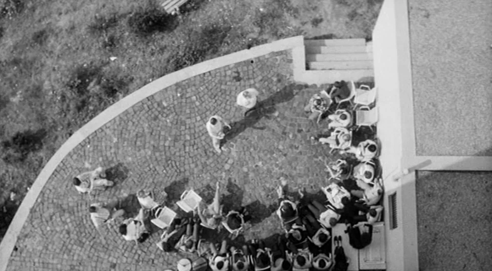 Kings of the Road (Im Lauf der Zeit) (1976) movie still: establishing — A stone-paved patio area sits beside a modern white building exterior. A…