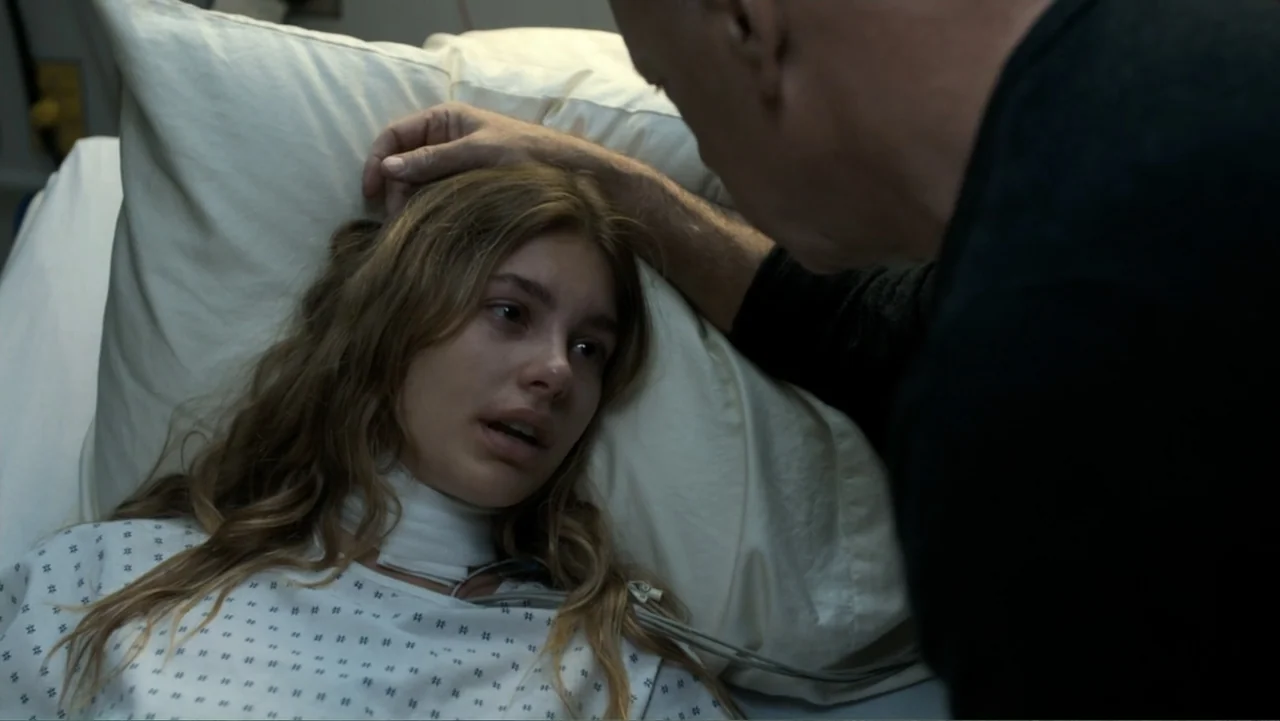 Death Wish (2018) movie still: medium — A sterile medical environment with a white pillow and hospital bedding. A young woman lies in bed while an…