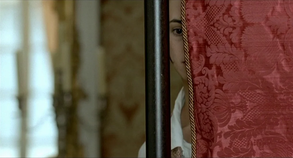 The Last Mistress (2007) movie still: closeup — An interior bedroom space features a patterned red fabric screen with an ornate border. A young…