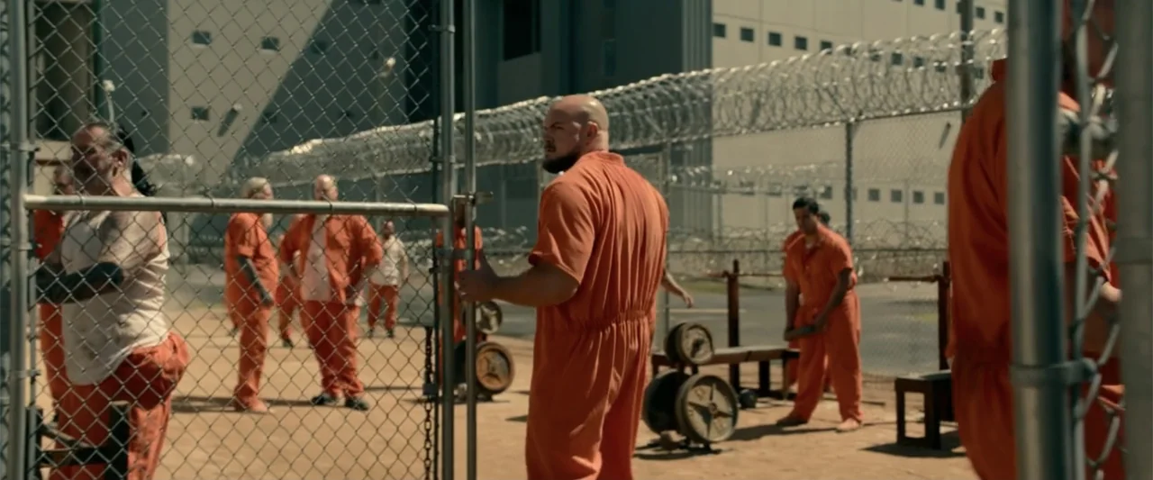 Bad Boys: Ride or Die (2024) movie still: fullbody — An outdoor exercise area enclosed by high chain-link fencing with coiled razor wire on top. A…