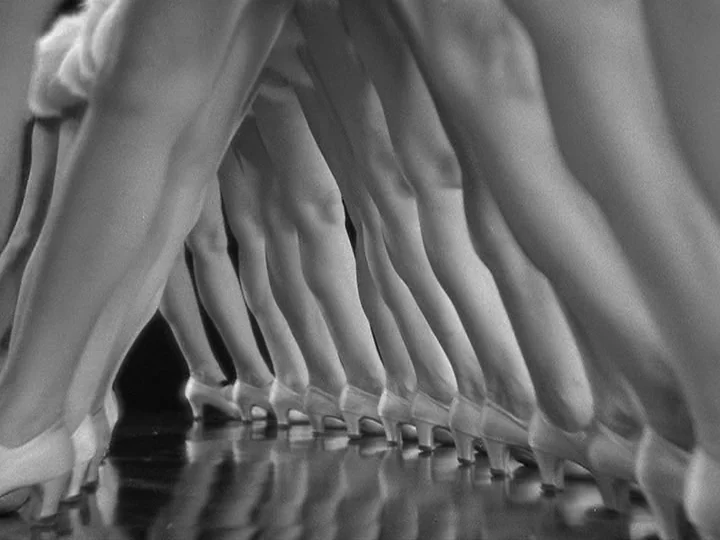 42nd Street (1933) movie still: medium — A row of legs in white heels performs a synchronized dance on a dark floor. The view is from a low angle…