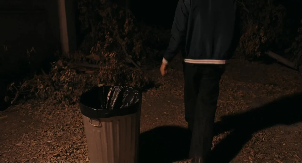 Ted Bundy: American Boogeyman (2021) movie still: medium — A dark outdoor space with scattered dried leaves on the dirt ground at night. A person…