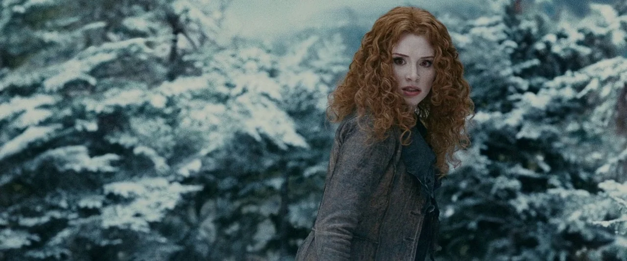 The Twilight Saga: Eclipse (2010) movie still: medium — A snowy forest with dense pine trees covered in a layer of white snow. A woman with long…