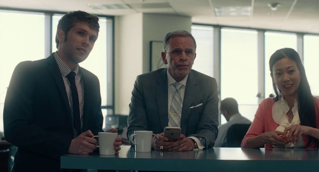 Roman J. Israel, Esq. (2017) movie still: medium — An corporate breakroom features a light blue counter and tall windows overlooking a city. Three…