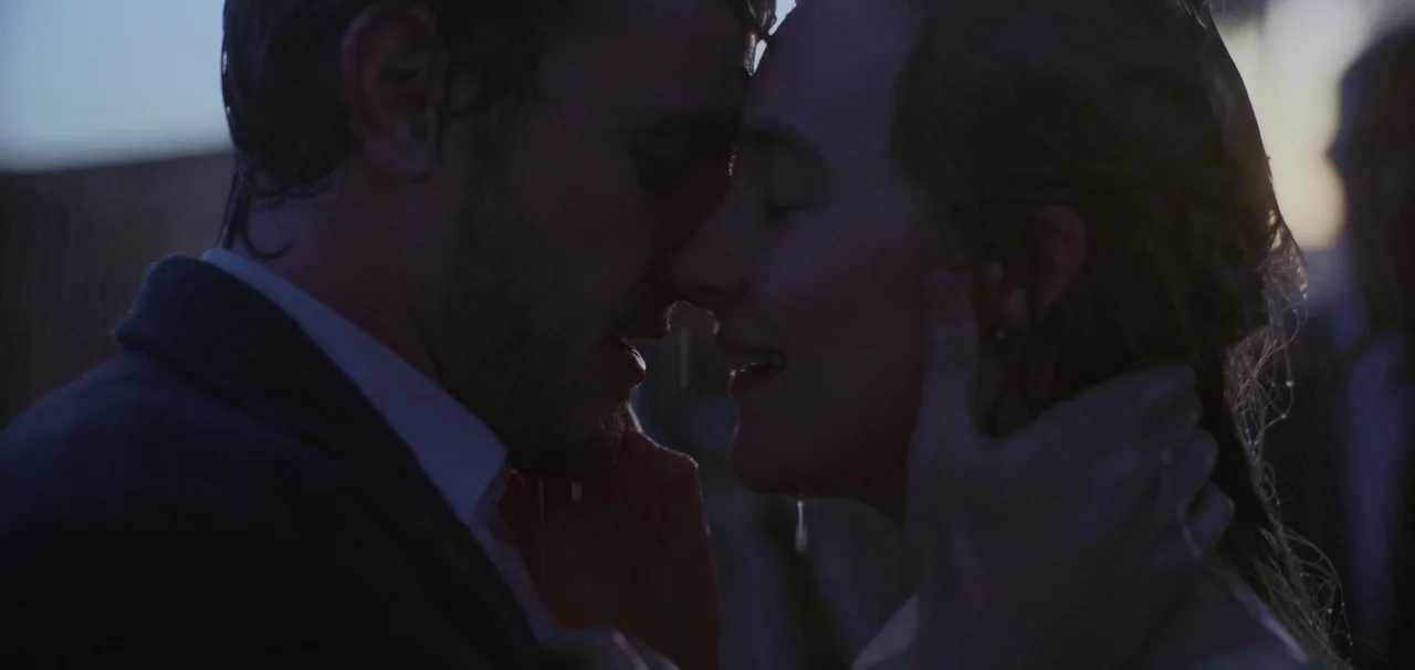Foe (2023) movie still: closeup — A close up of two people standing face to face in the rain. They touch foreheads with their eyes closed as water…