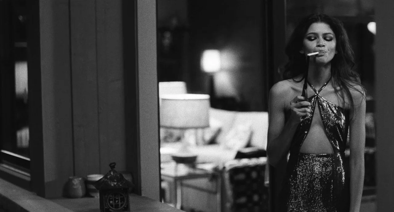 Malcolm & Marie (2021) movie still: medium — A modern living space features blurred furniture and lamps in the background. A young woman in a…
