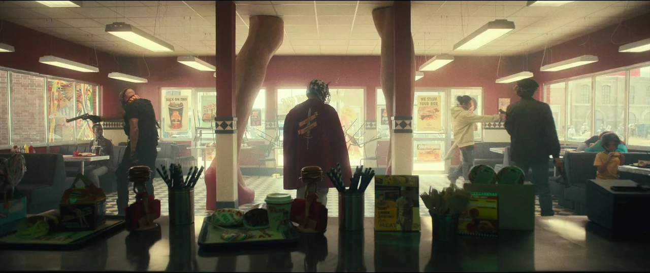 The Toxic Avenger (2023) movie still: wide — A fast food restaurant features two giant human-shaped pillars standing from floor to ceiling. Armed…