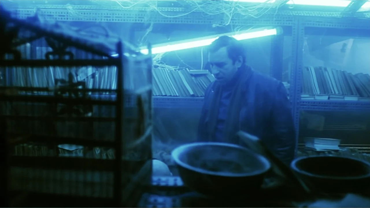O-Bi, O-Ba: The End of Civilization (1985) movie still: medium — A dark, cramped room contains metal storage shelves filled with stacks of papers. A…