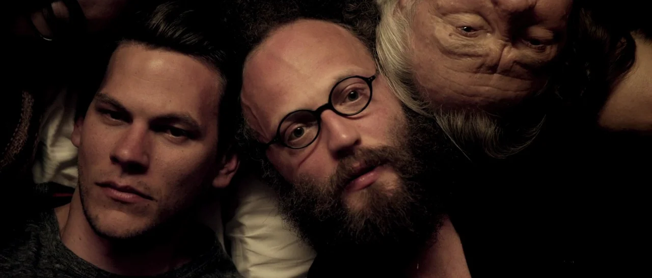 Youth (2015) movie still: closeup — Three men lie on a pillow while viewed from a direct overhead camera angle. Their faces are closely clustered…