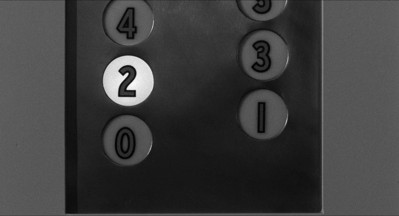 A Face In The Crowd (1957) movie still: closeup — A metal elevator control panel features circular buttons numbered zero through four. The button…