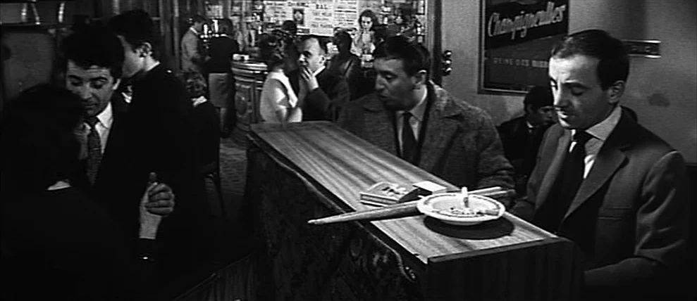 Shoot The Piano Player (Tirez Sur Le Pianiste) (1960) movie still: medium — A dimly lit European bar features patrons standing along a polished…