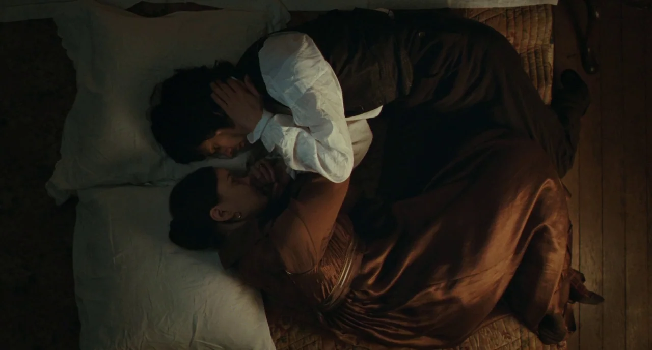 Bright Star (2009) movie still: medium — A dimly lit room features two people lying on a mattress on a wooden floor. One person lies over the other…