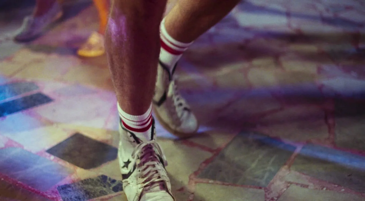 Call Me By Your Name (2017) movie still: closeup — A stone tiled dance floor has irregular paving patterns in shades of gray. A person's legs…