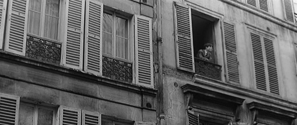 Antoine and Colette (1962) movie still: wide — A multi-story stone apartment building features several windows with wooden shutters and iron…