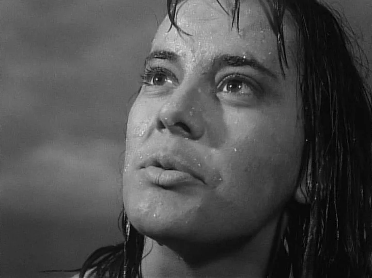 Knife In The Water (1962) movie still: closeup — A close-up shot focuses on a person's face inside a shower stall. Water droplets are visible on the…