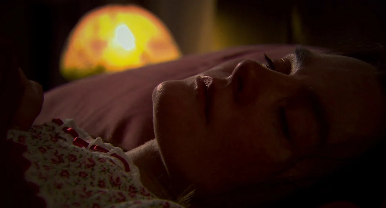 Everyday (2012) movie still: closeup — A close-up view shows a person sleeping in a dark bedroom at night. An illuminated lamp glows behind the…