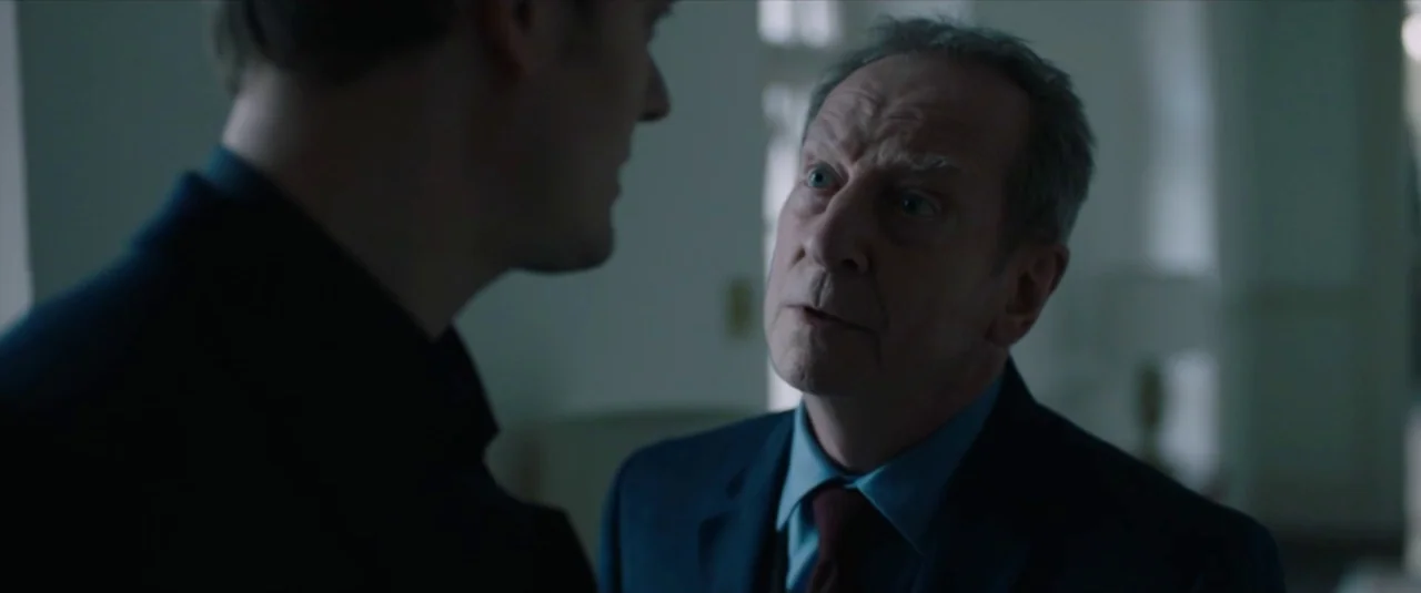 Happy New Year, Colin Burstead (2018) movie still: medium — A dimly lit room with cool-toned lighting and plain, indistinct walls. An older man…
