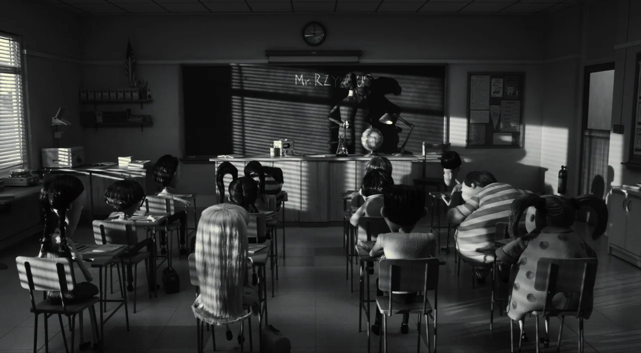 Frankenweenie (2012) movie still: wide — A dark classroom with rows of student desks facing a front blackboard. A teacher stands at the front board…