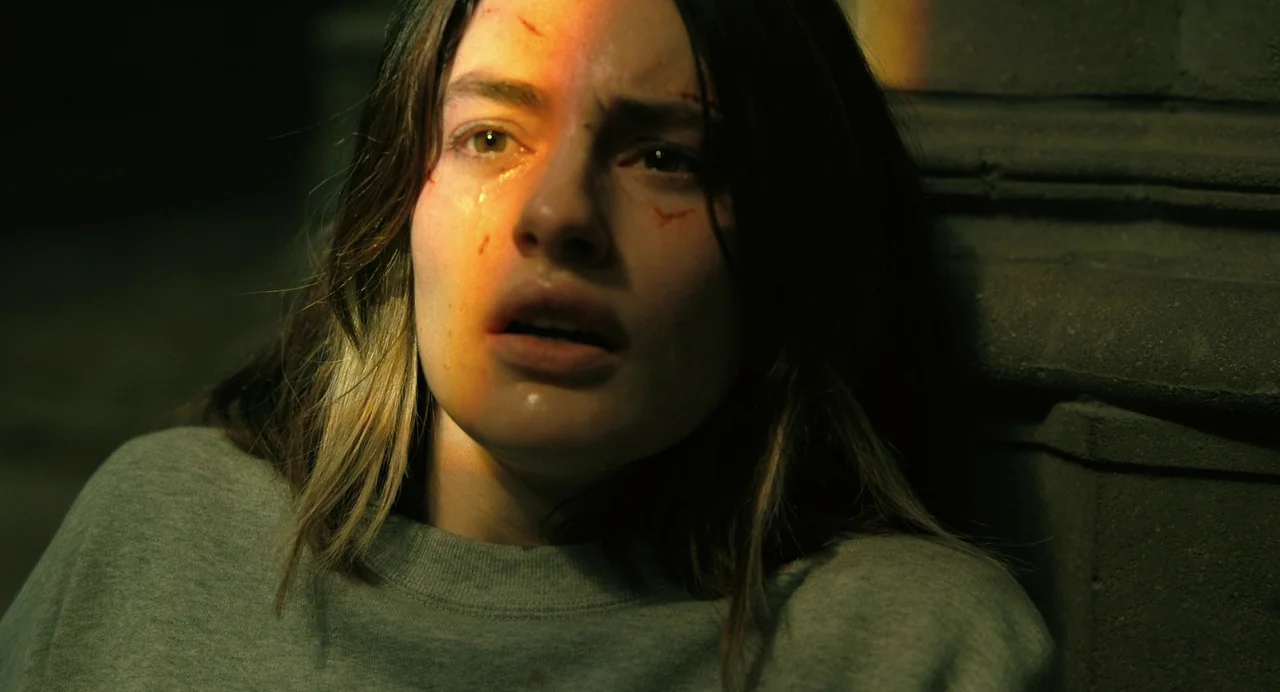 The Killer (2024) (2024) movie still: closeup — A dark corner with a textured masonry wall provides the backdrop for a close-up. The subject rests…