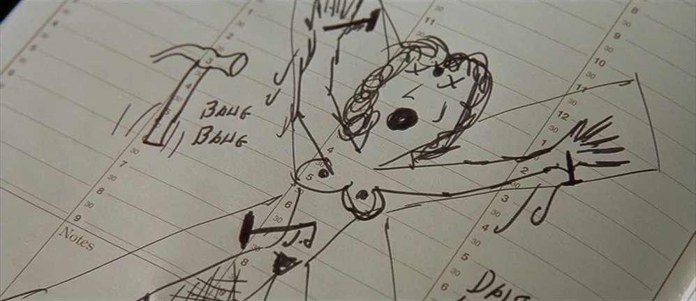 American Psycho (2000) movie still: closeup — A close-up view of a daily planner page with printed lines and text. A crude ink drawing shows a…