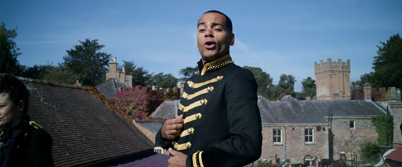 Cinderella (2015) movie still: medium — A man stands on a rooftop with brick buildings and a stone tower visible. The man wearing a black…