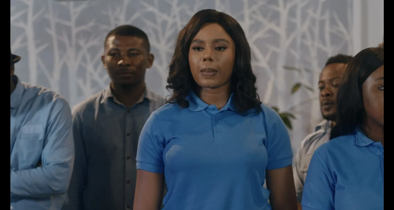 Love In A Pandemic (2023) movie still: medium — A light blue wall with a white tree branch graphic serves as the background. Several people in…