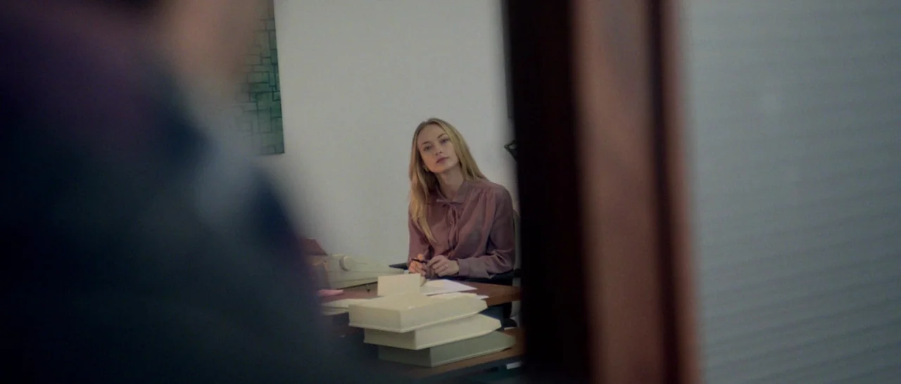 Nymphomaniac Vol 1 (2013) movie still: medium — A workspace featuring a desk with paper stacks and a vintage manual typewriter. A woman sits behind…