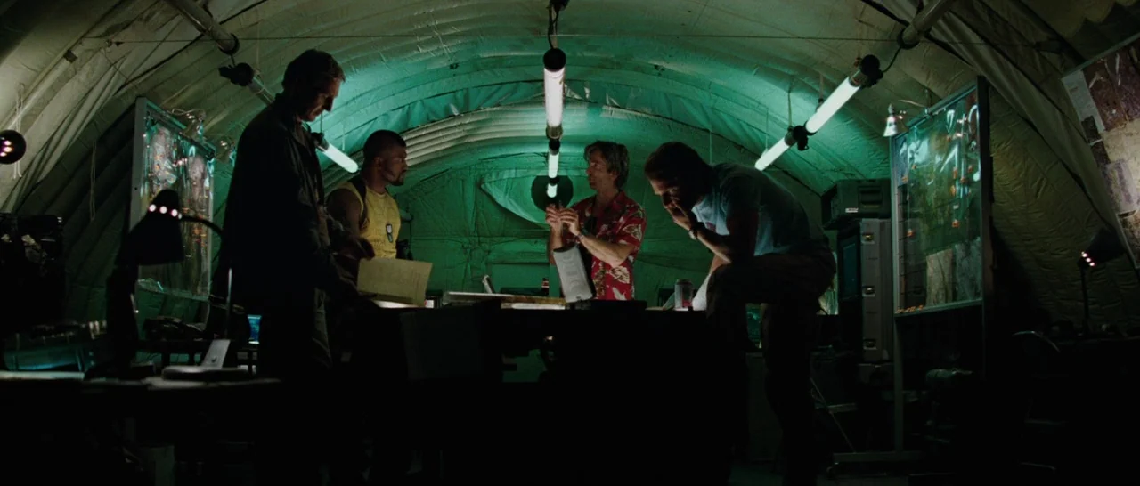 The A-Team (2010) movie still: wide — A curved military tent interior features green canvas walls and dangling fluorescent light fixtures. Four men…