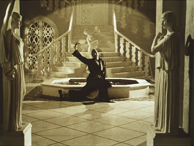 All These Women (1964) movie still: wide — A grand foyer features a tiled floor, central fountain, and decorative classical statues. A man kneels by…