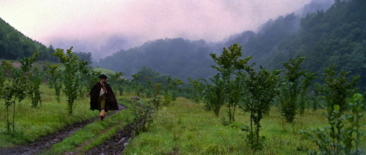 Night of the Blood Monster (1970) movie still: wide — A rural landscape features rolling hills with a muddy track between rows of saplings. A lone…
